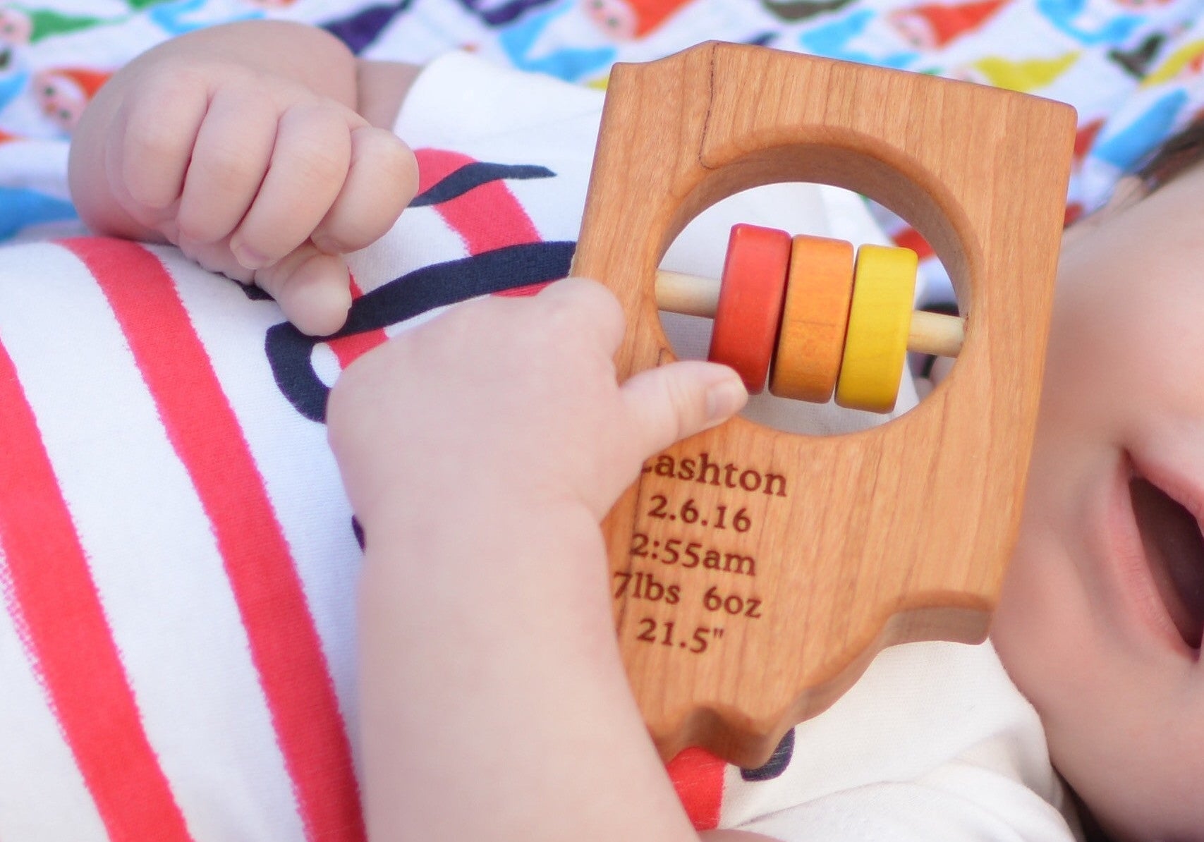 baby holding Indiana State Wooden Baby Rattle™ - Bannor Toys