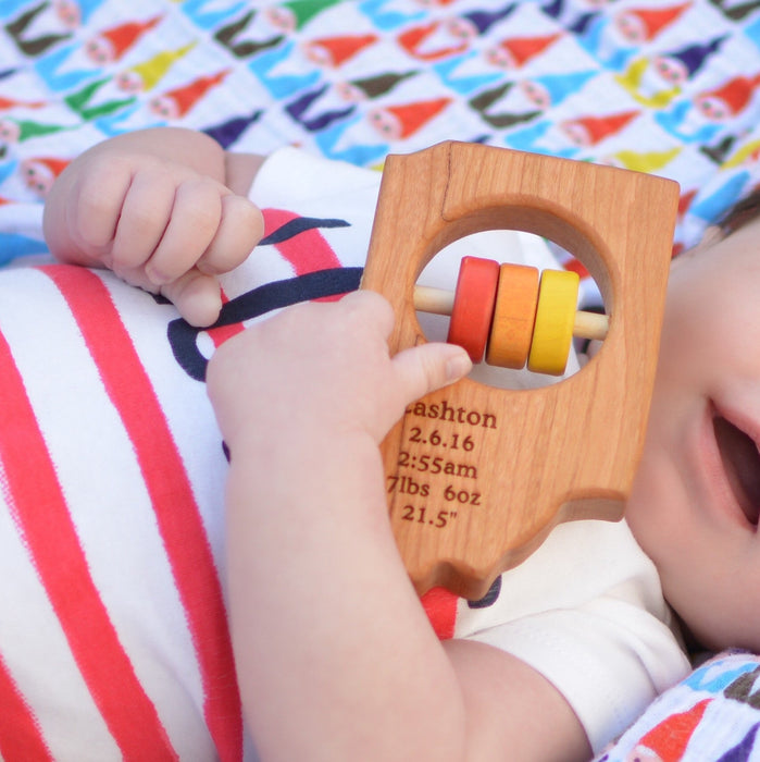 baby holding Indiana State Wooden Baby Rattle™ - Bannor Toys